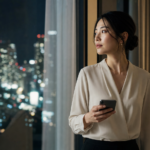 夜景を見つめながらスマホを持ち、既婚者への恋に悩む日本人女性